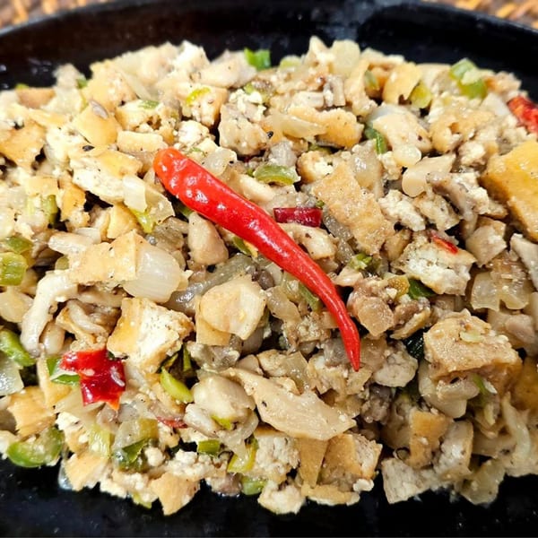 Close-up of Kusinera Filipino Cuisine's sisig, a sizzling dish with chopped meat, onions, and chili.