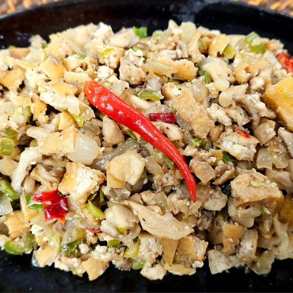 Close-up of Kusinera Filipino Cuisine's sisig, a sizzling dish with chopped meat, onions, and chili.